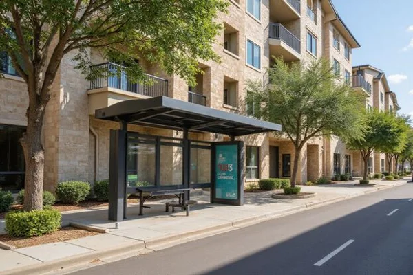 Shaded bus stop in front of a mid-rise apartment building