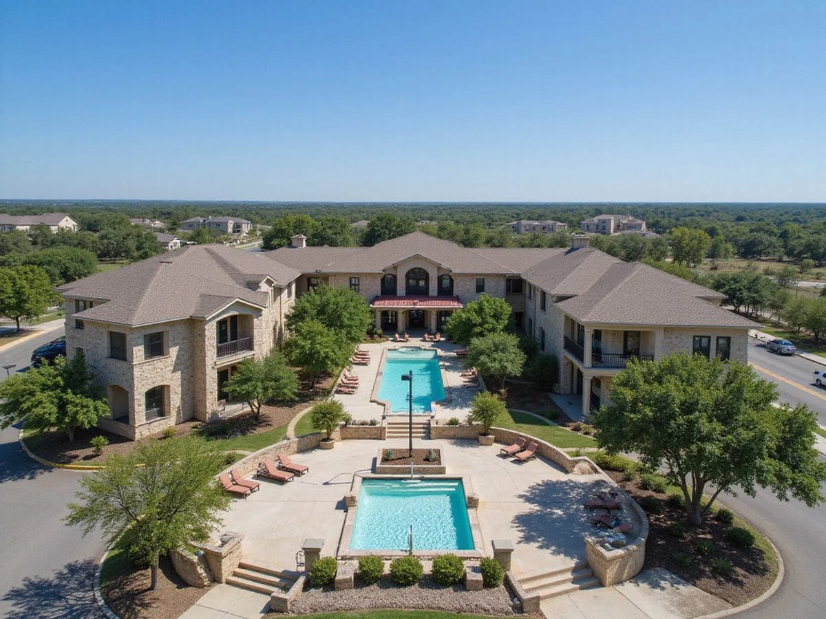 Aerial view of a brand-new San Antonio apartment community with a pool courtyard and limestone buildings